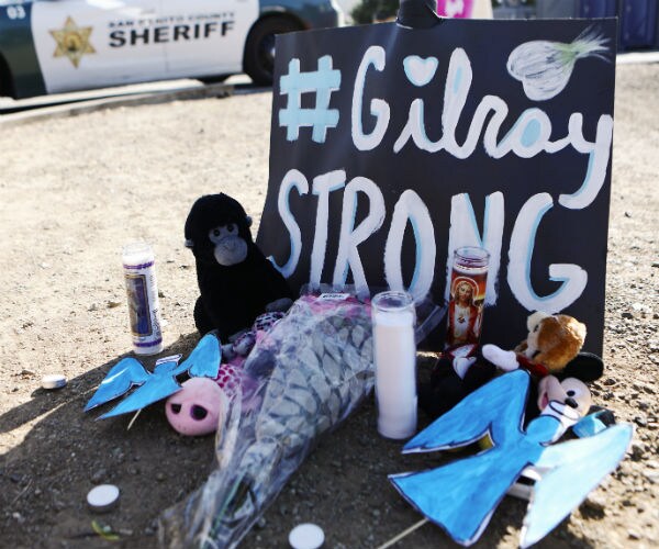 a signs says gilroy strong and is surrounded by a candle and other mementos