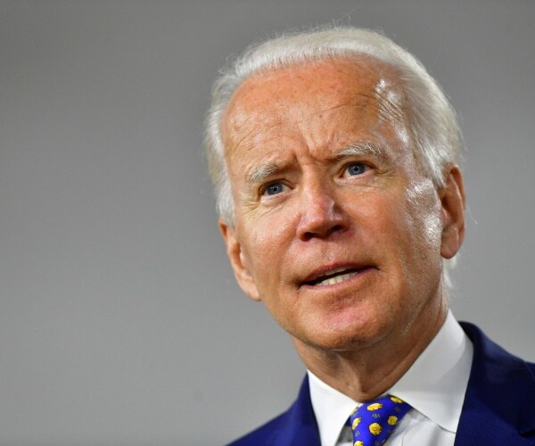 biden in a suit and blue and yellow tie with gray background