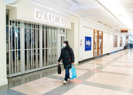 a person in a mask walks past a store
