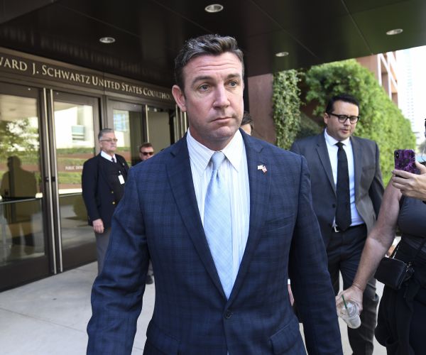 Duncan Hunter walks out of a building and is photographed by paparazzi