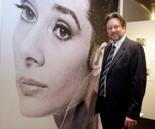 sean ferrer stands next to image of audrey hepburn