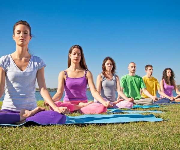 line of men and women meditating outside in a field