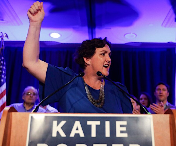 Katie Porter raises arm while speaking into a microphone