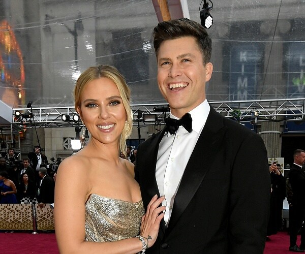 scarlett johansson and colin jost stand on red carpet