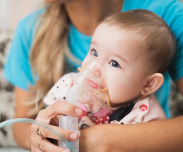 mother doing a breathing treatment with baby 
