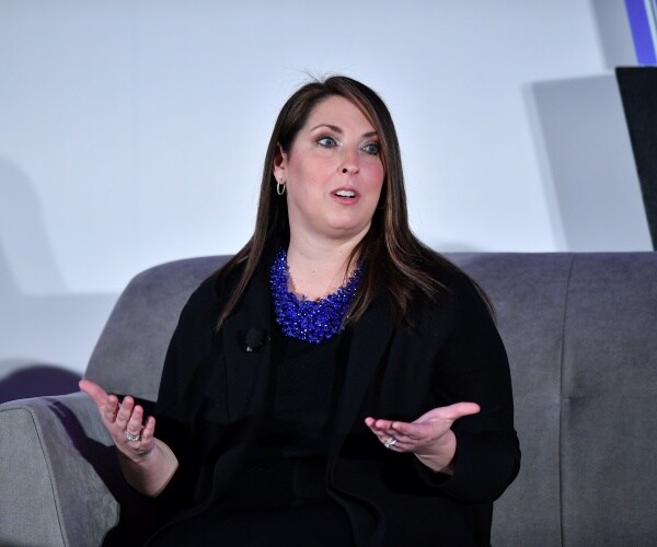 ronna mcdaniel in a black dress and coat and blue necklace speaking on stage