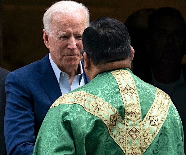 president joe biden greets a catholic priest in a robe