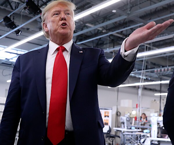 president donald trump gestures with his left hand while visiting a factory