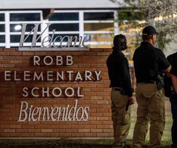law enforcement officers speak together outside of robb elementary school
