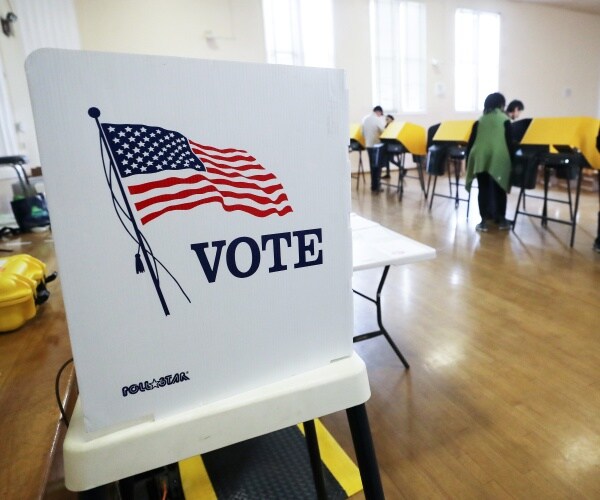 voting booth is shown with poll workers and people voting