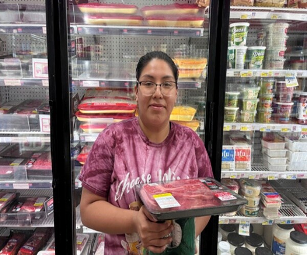 consumer holding a package of meat in supermarket