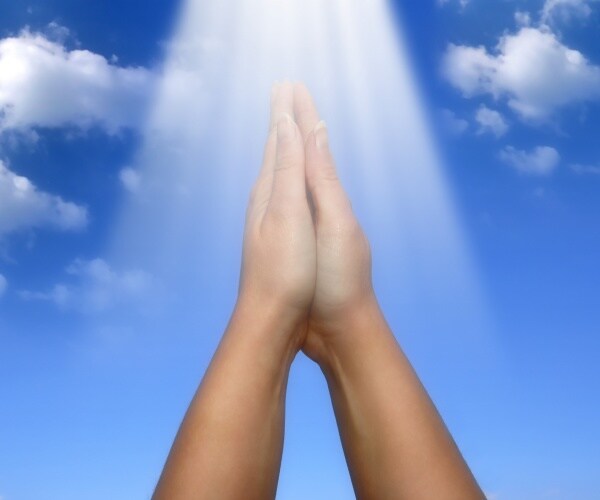 rays of light falling on a female hands in prayer gesture