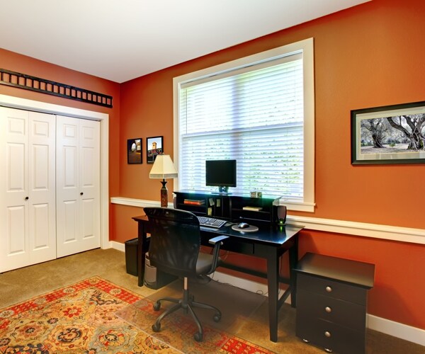 a home office with orange walls and brown furniture