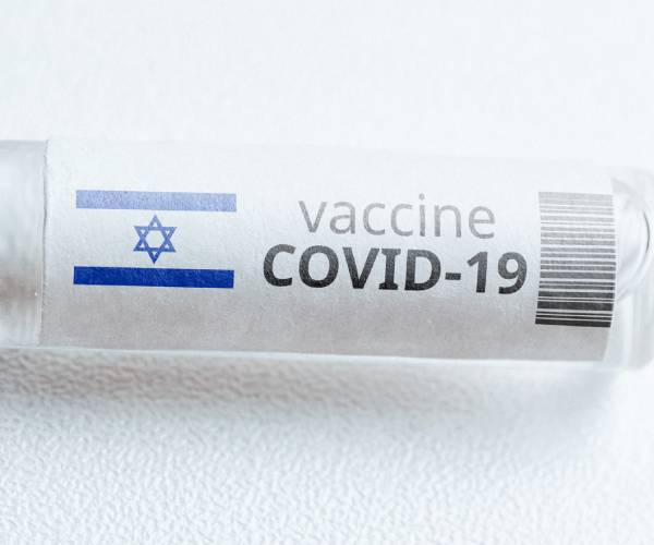 a vial of covid vaccine with an israeli flag