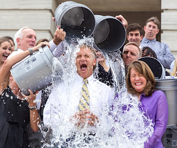 a man and a woman get buckets of ice water dumped on them