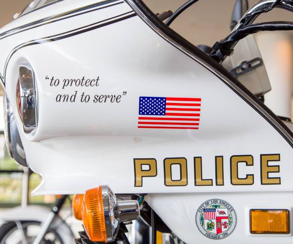 side of a police motorcycle with logo reading police and to protect and serve