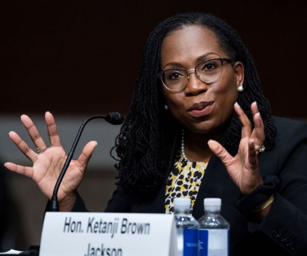 Ketanji Brown Jackson gestures with both hands from behind a microphone