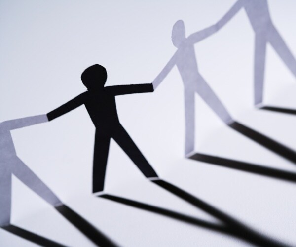 one black cutout paper person holding hands with group of white people