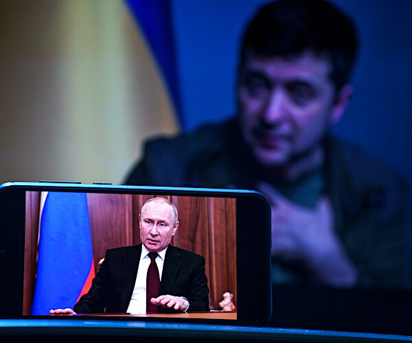 volodymyr zelenskyy speaks with vladimir putin speaking on a cell phone in front of his screen