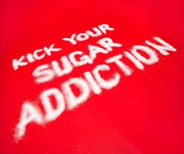 Kick Your Sugar Addiction spelled out with sugar on a red background