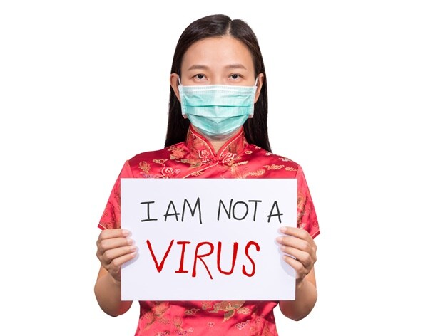a asian woman holds a sign  saying she is not the coronavirus