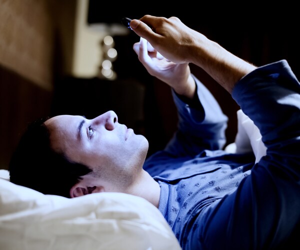 a man reading his phone in bed