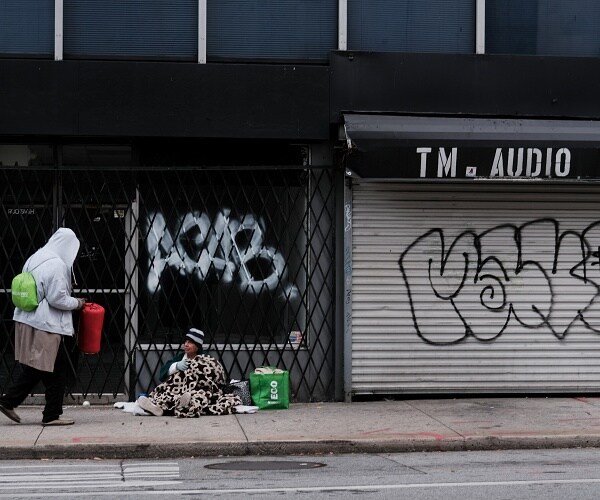 person walks past homeless man on empty street