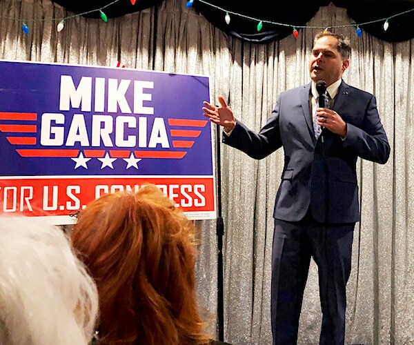 mike garcia campaigns holding a mic during a indoors rally