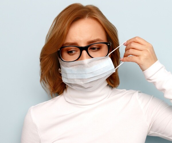 woman wearing glasses, white turtleneck top, and a face mask 