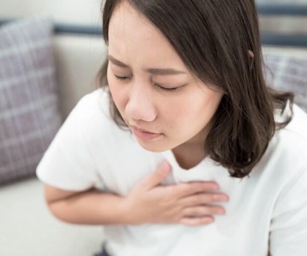 woman in a white t shirt with throat and chest pain