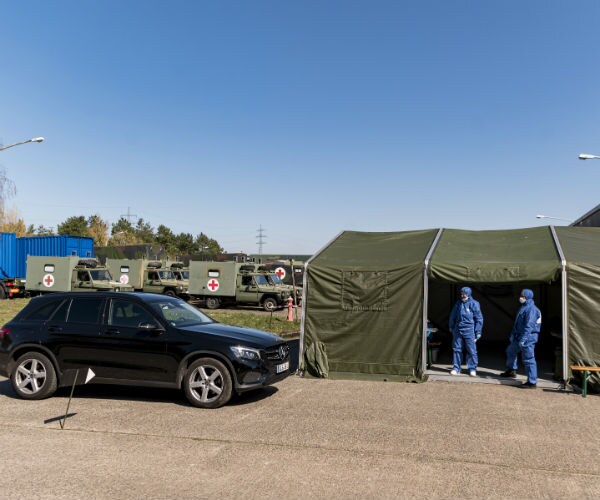 military medics are shown in green military tents in a make shift drive-thru for virus testing