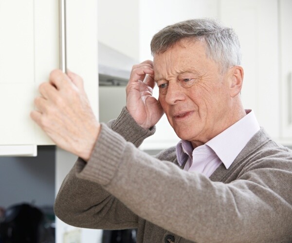 man looking forgetful as he looks in cabinet