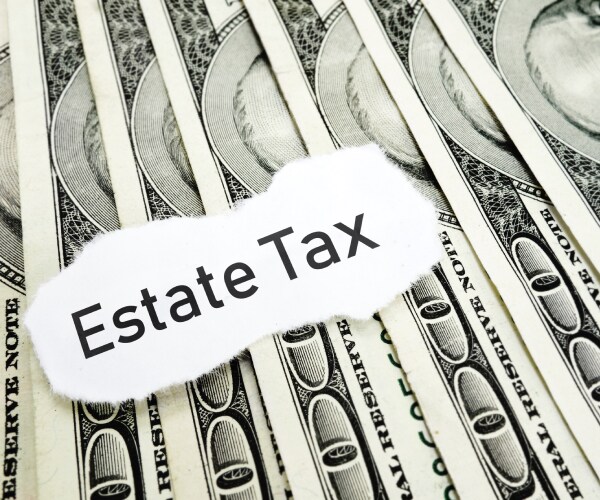 the words estate tax written over fanned out one hundred dollar bills