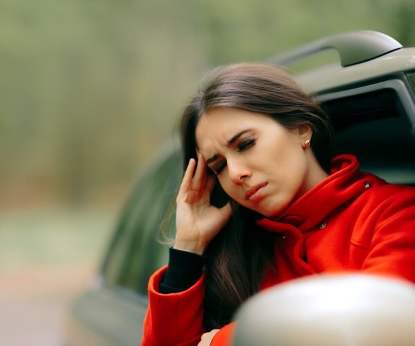 woman with motion sickness sticking head out window of car 