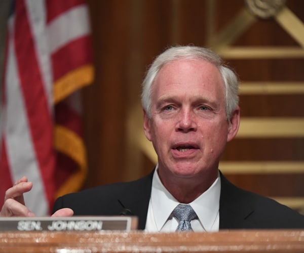ron johnson sits at a desk during a senate hearing