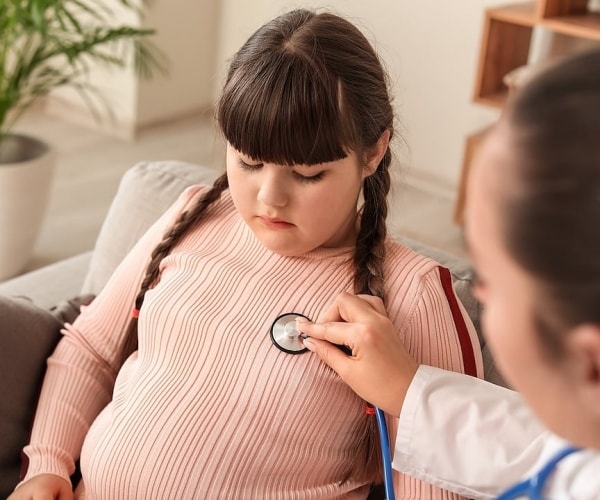 doctor using stethoscope to listen to a young overweight girl's chest