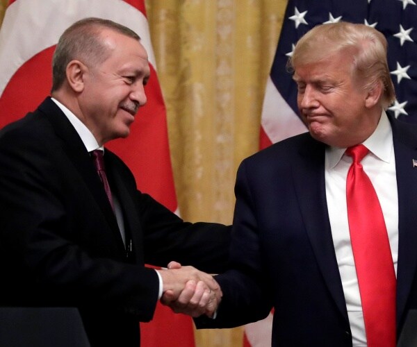 erdogan and trump shake hands both wearing suits and trump in a red tie in front of us and turkish flags