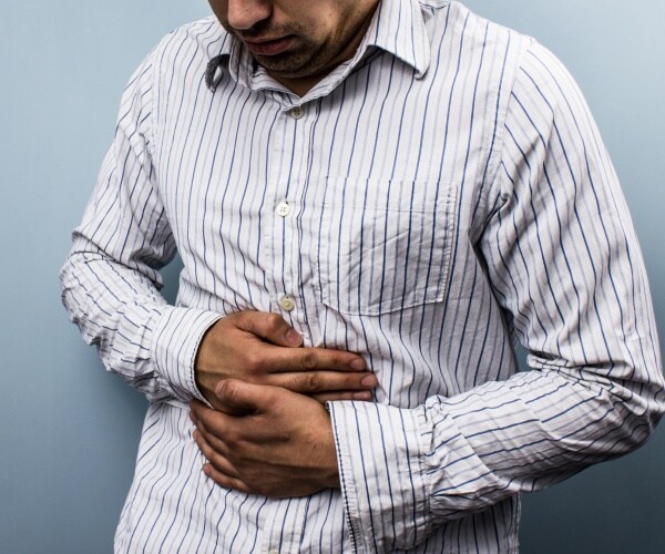 man with constipation holds stomach in pain