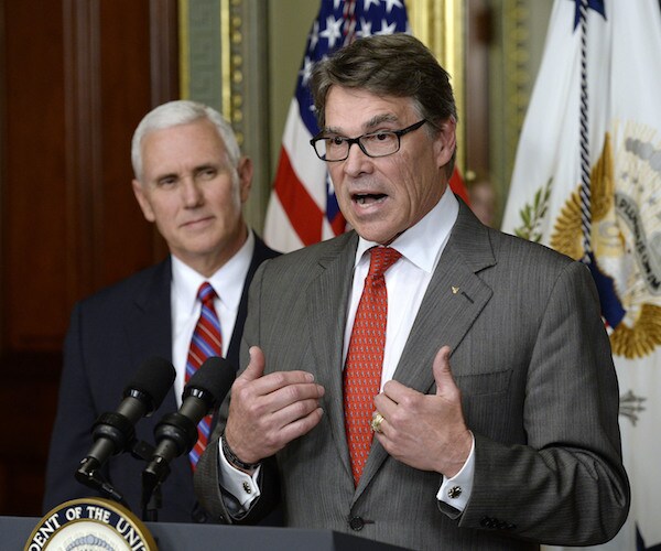 energy secretary rick perry stands and gestures with both hands during a news conference with mike pence behind him