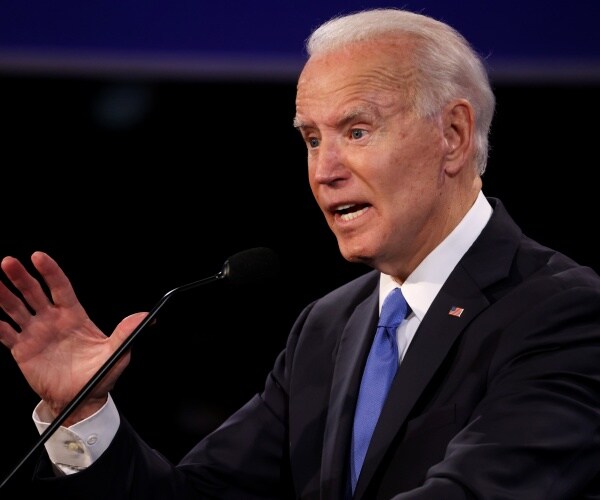biden in a black suit and blue tie speaking at the debate