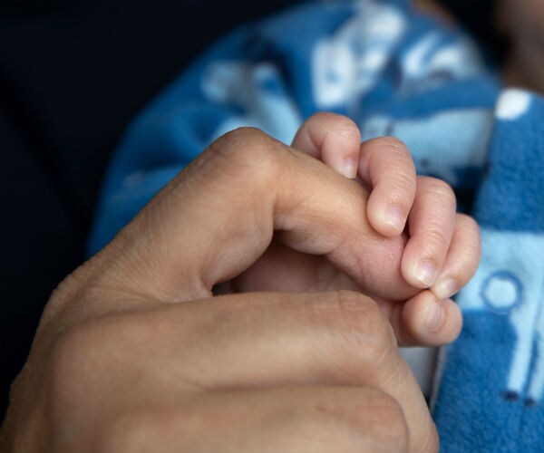 an adult hand is shown embracing an infant hand
