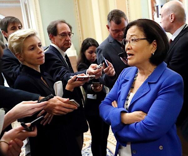 mazie hirono folds her arms as she speaks to a throng of media