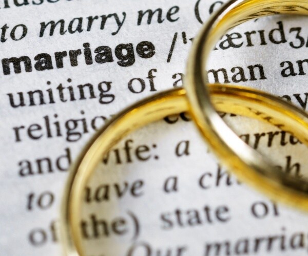 two wedding rings next to the word marriage on a dictionary
