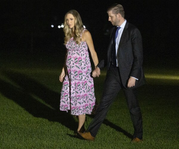 a pregnant lara trump wears a pink and green sundress while holding hands with eric trump