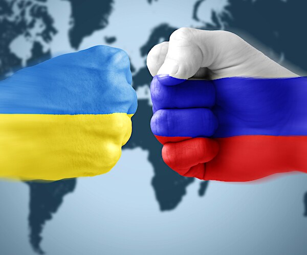 a fist painted in ukraine flag colors collides with a fist painted in russia's flag colors