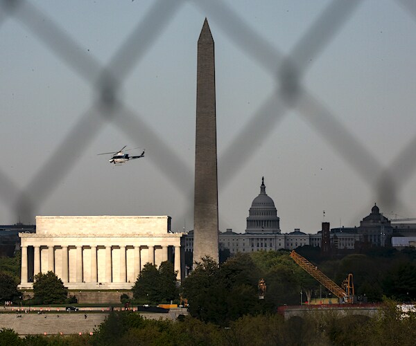 helicopter flies over Washington's National Mall with the washington monument and white house in the background