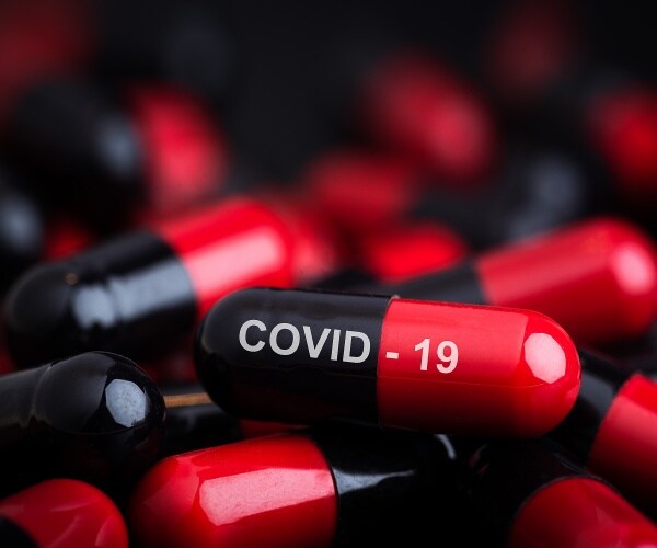 a bunch of medication capsules, COVID-19 written on one