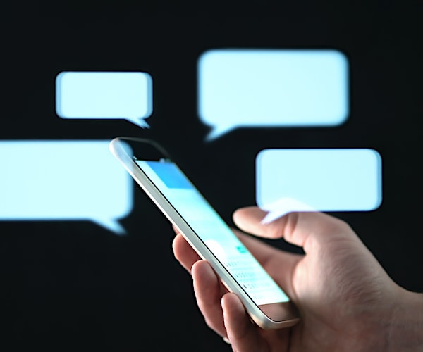 ext messages in cellphone screen with abstract hologram speech bubbles. Instant messaging app. Texting