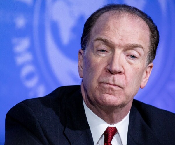 david malpass, president of the world bank group, in a suit in front of a blue background with an imf logo