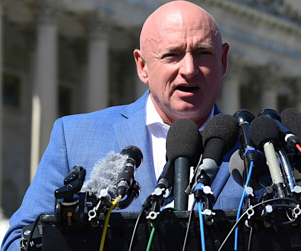 retired astronaut mark kelly speaks into a gaggle of mics with capitol hill in the background